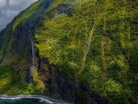 waterfalls cascading down valley walls and vertical sea cliffs molokai hawaii