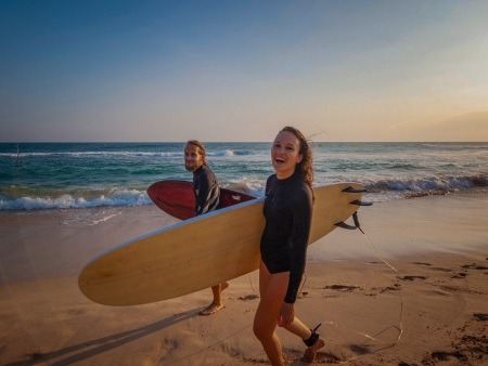 young couple of happy smiling surfers on ocean coast