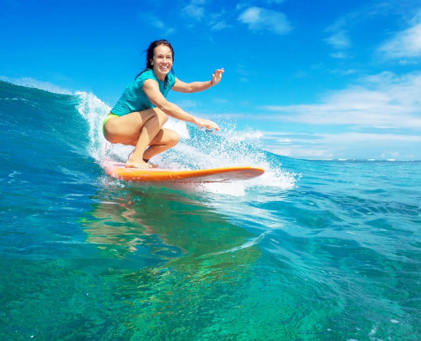 beautiful girl surfing on big transparent waves maui