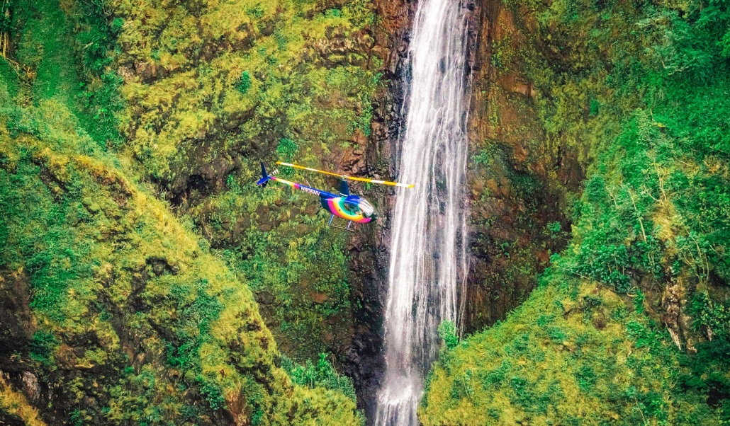 scared falls surrounded by rocky cliffs and greenery oahu rainbow helicopters