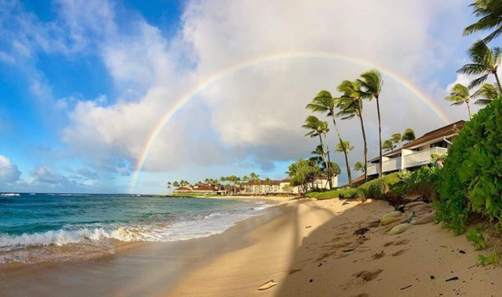 surfing under a rainbow in poipu kauai