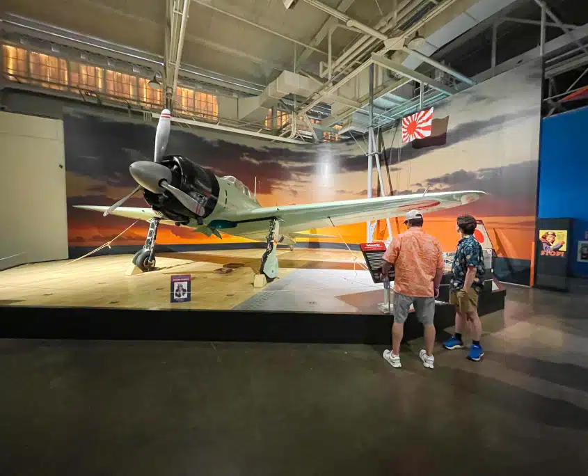 Japanese Zero fighter plane on display at the Pacific Aviation Museum Pearl Harbor with visitors viewing the exhibit
