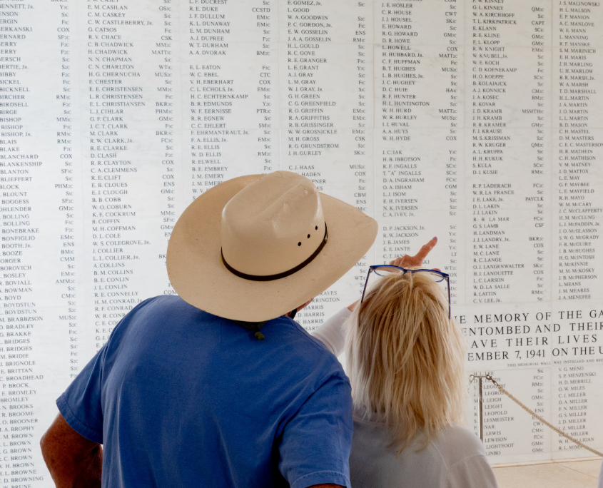 Visitors looking at the USS Arizona Memorial wall of names honoring fallen sailors and Marines at Pearl Harbor