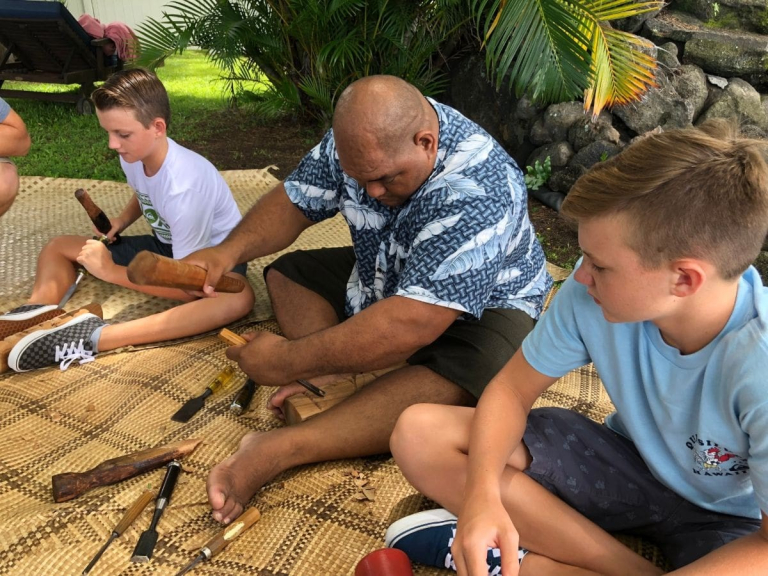 Aloha-Adventure-Farms-people-carving-wood-together-on-woven-mat