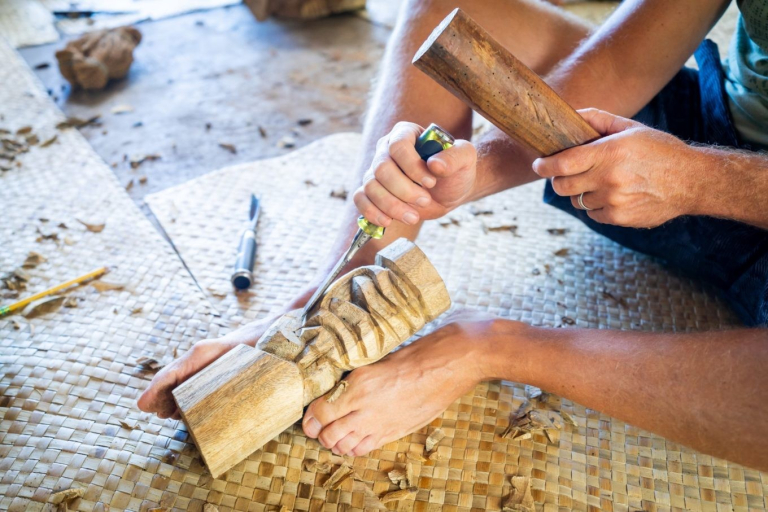Aloha-Adventure-Farms-person-carving-wooden-sculpture-on-woven-mat