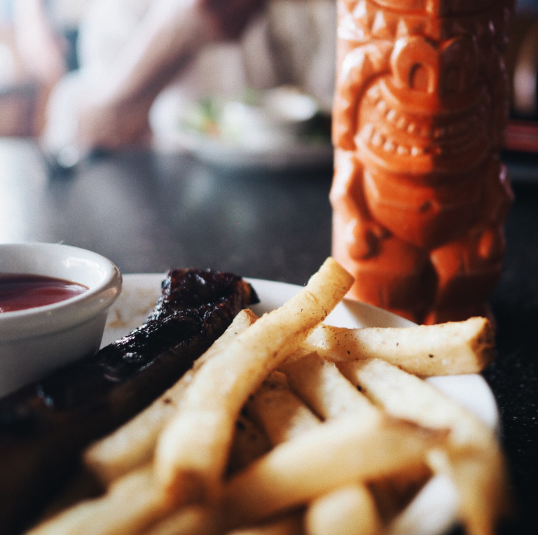 Tasting-Kauai-fries-and-ribs-with-tiki-mug-nearby
