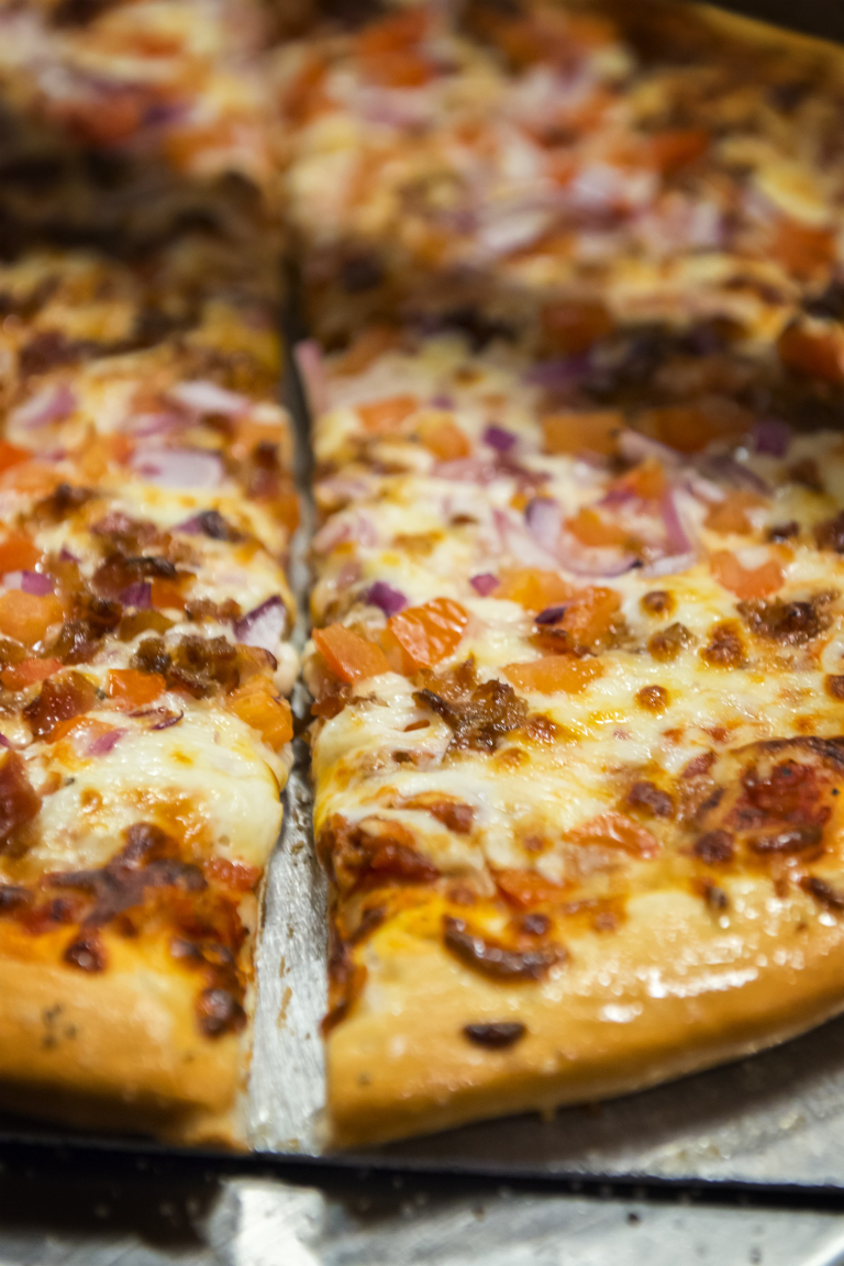 Tasting-Kauai-sliced-pizza-with-toppings-on-tray