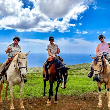 Palehua Trail Rides - three people horseback riding on grassy hill